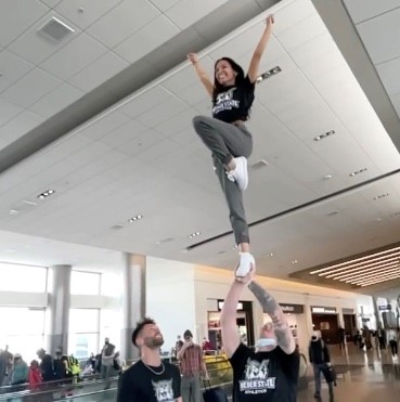 Photo shows a cheerleading stunt inside of an airport.