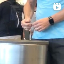 Individual publicly clipping their nails over an airport trash can