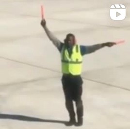 Individual directing a plane on the airport tarmac