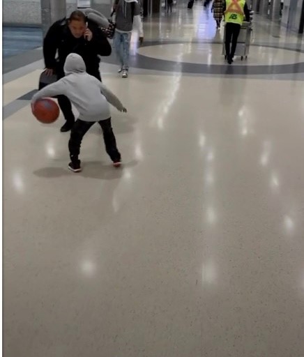 A young child playing basketball in an airport