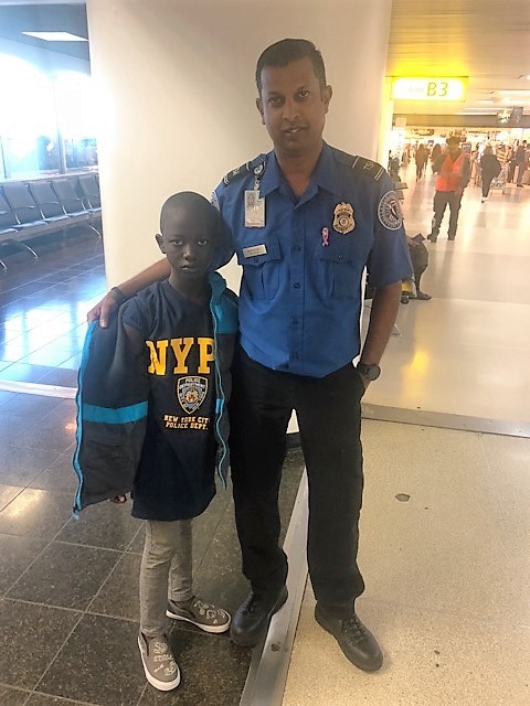 Lead TSA Officer Ravi Rampersad with young boy who came to LaGuardia Airport with his coat, but no shirt. Rampersad and a colleague purchased a T-shirt for the young boy. (TSA photo)