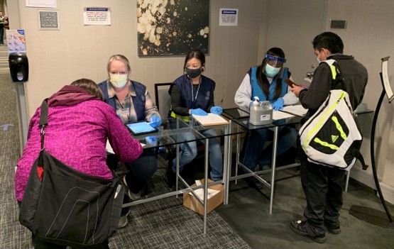 Members of TSA’s Surge Capacity Force who are working for FEMA in Chicago at a vaccination site, staff the registration desk as people come in for their vaccines.