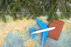 Plane and passport on a map next to evergreen tree branches