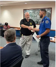 Palm Beach County Sheriff’s Office Detective Ken Smith presents TSA Officer Ryan Perreault with the Palm Beach County Palm Crime Stopper Award at the monthly Palm Beach International Airport/Stakeholders meeting.  (Photo by Joseph Aiuto)