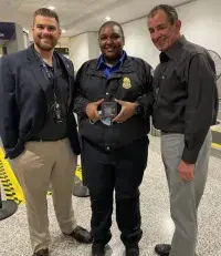 MIA TSA Assistant Federal Security Director Adam Ostrowsky (left) and Deputy Assistant Federal Security Director John Brehm honor Lead TSA Officer Shanquita Auguste with a TSA coin for her role in saving a passenger’s life. (Photo courtesy of TSA MIA)