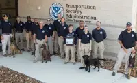 Canine handlers and their canines with the 9/11 flag during the 2022 TSA DHS flag tour at the TSA Canine Training Center in San Antonio. Supervisory Training Instructor Virginia Beauman is holding the flag in the middle. (Photo by Josh Wagner)