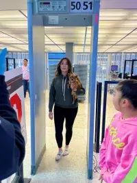 Travelers should hold their pet as they walk through the metal detector. Alternatively, the pet can be walked through the metal detector on a leash. (TSA photo)