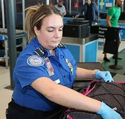 TSA Officer Shelly Myers conducts a bag search at a JFK checkpoint. (Photo by Zhilin Ye)